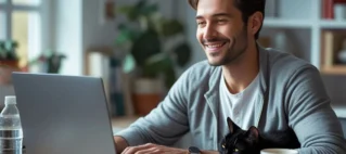 homem trabalhando em home office olhando para notebook com um gatinho ao lado, ilustrando direitos do trabalhador remoto