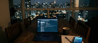 Laptop ligado sobre mesa de jantar em ambiente residencial à noite com celular recebendo notificações de trabalho.